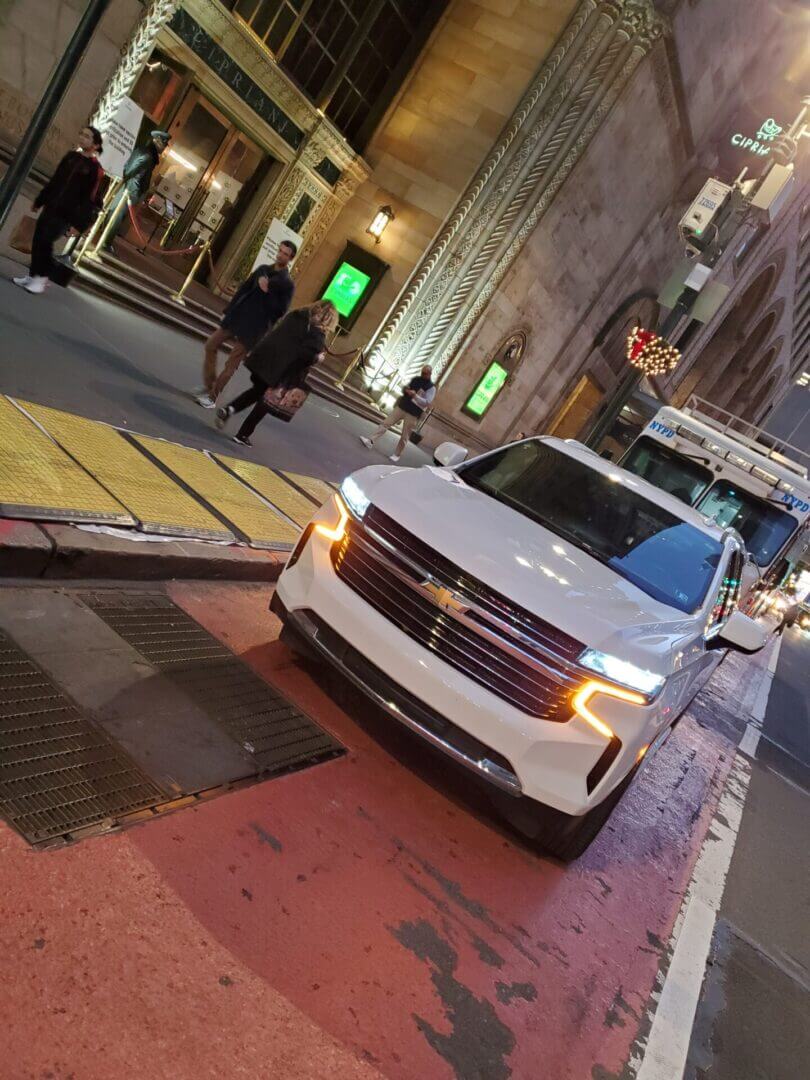 White SUV parked on busy city street.