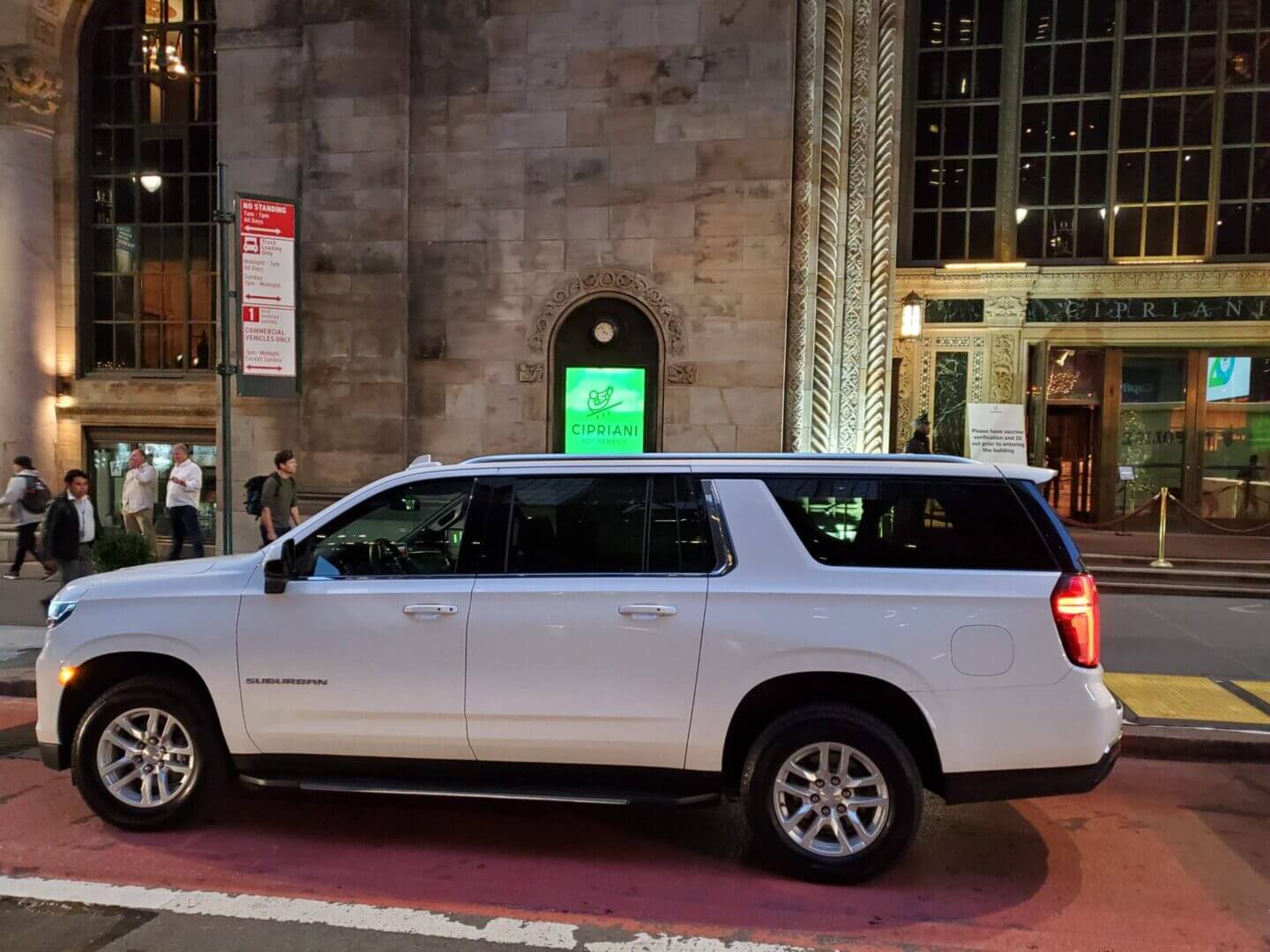 White SUV parked on city street at night.