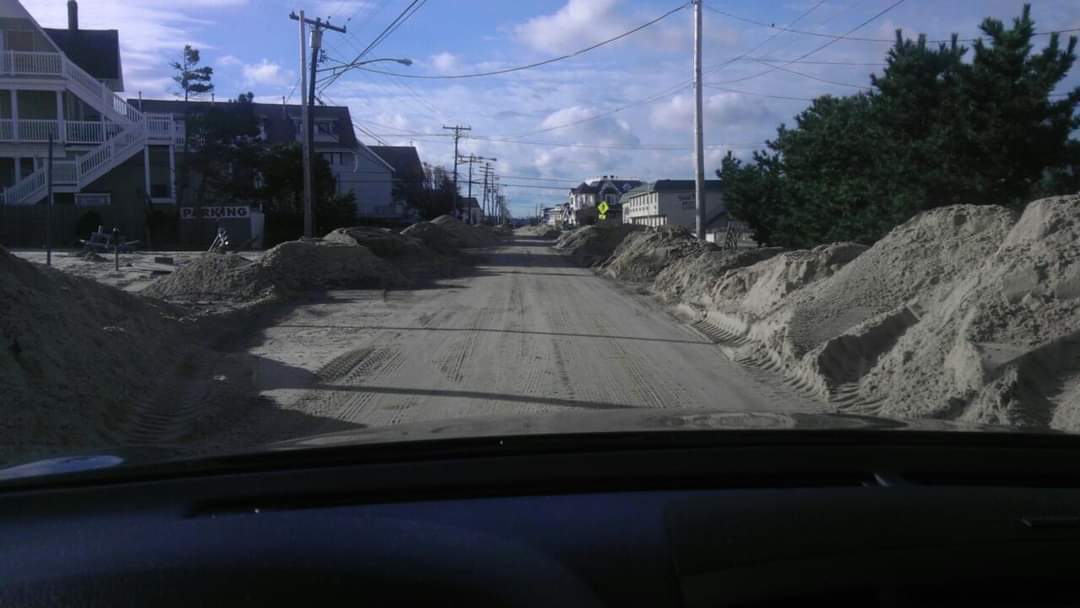 Sandy road with houses and clear sky.