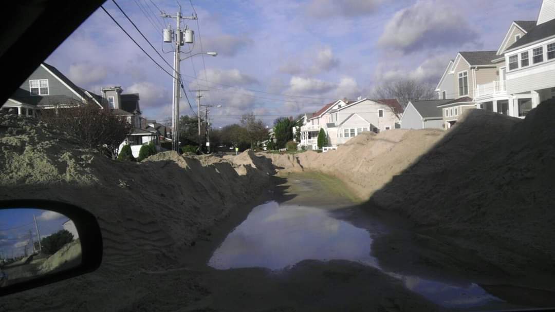 Flooded sandy road between residential houses.