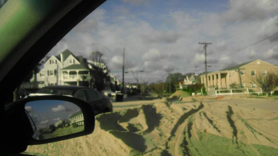 Sandy street with houses and parked cars.