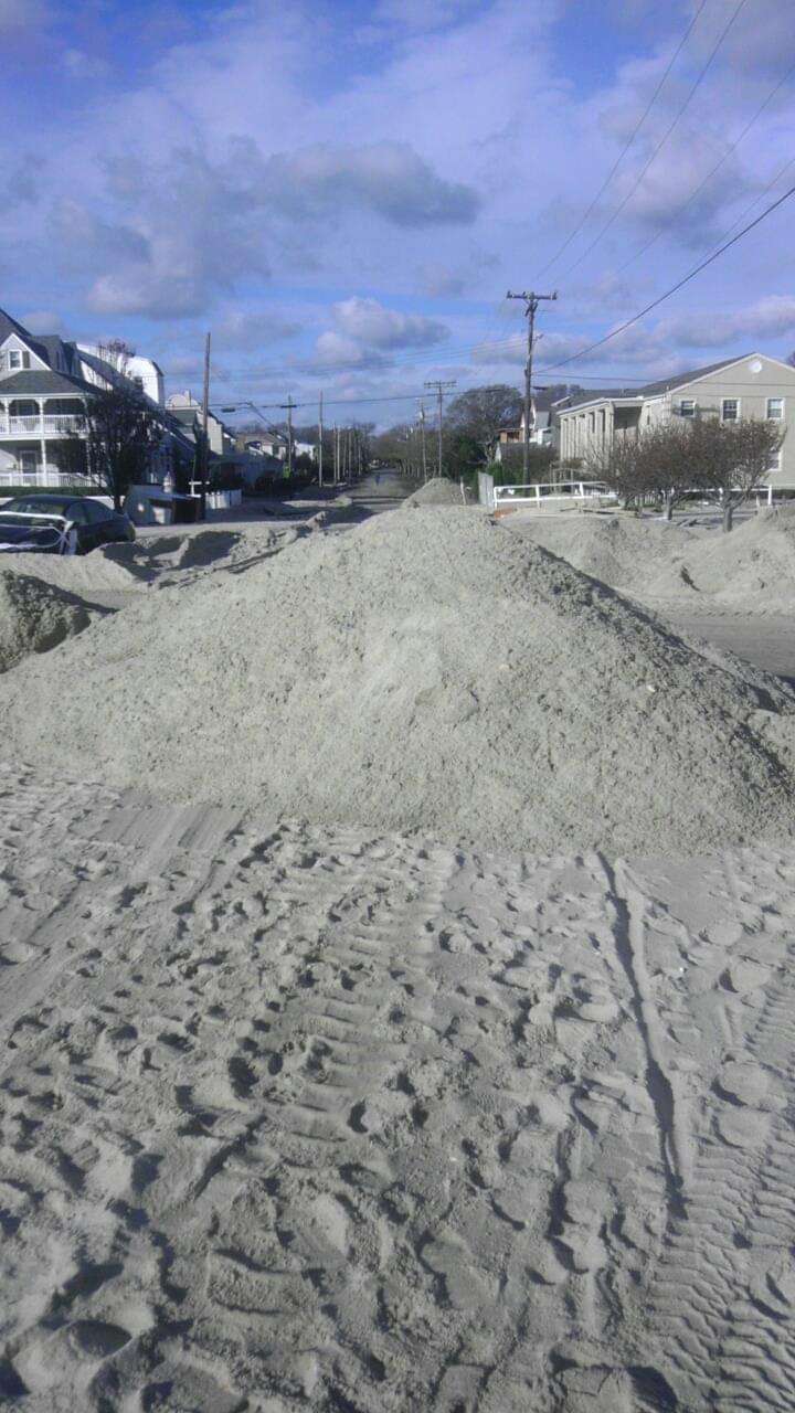 Sandy street with piled sand and houses.