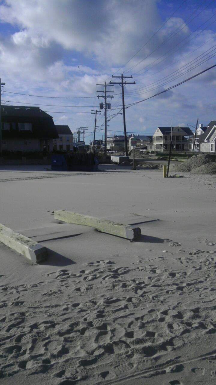 Sandy beach with cloudy sky and houses.