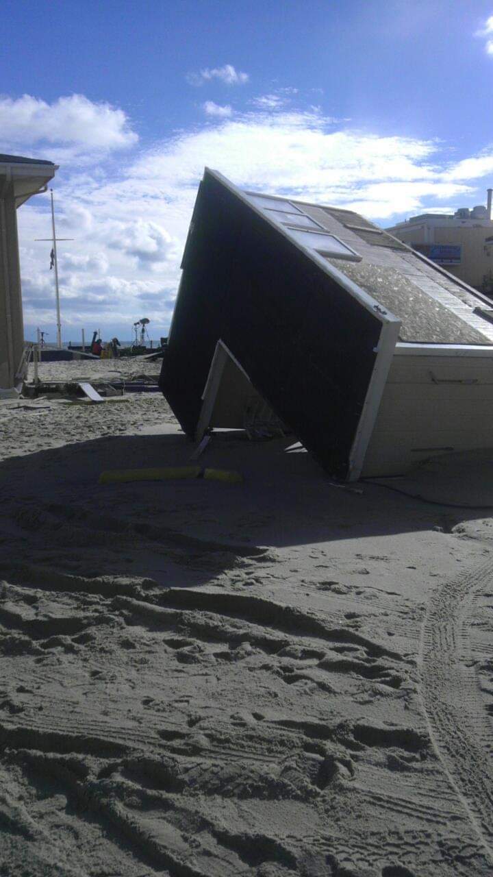 House tipped over on sandy beach.
