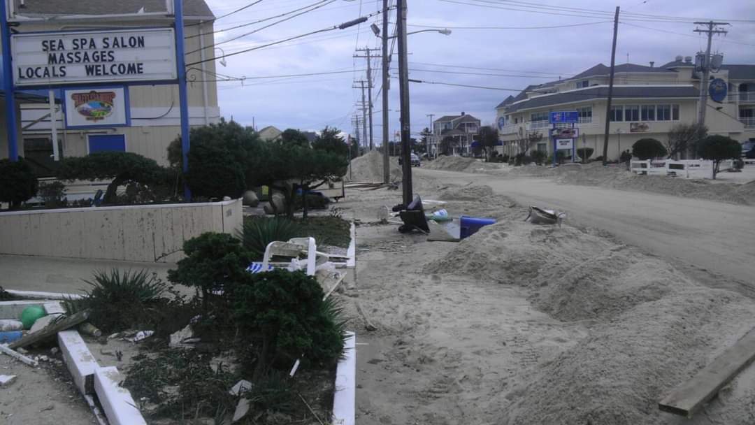 Street covered in sand with damaged surroundings.