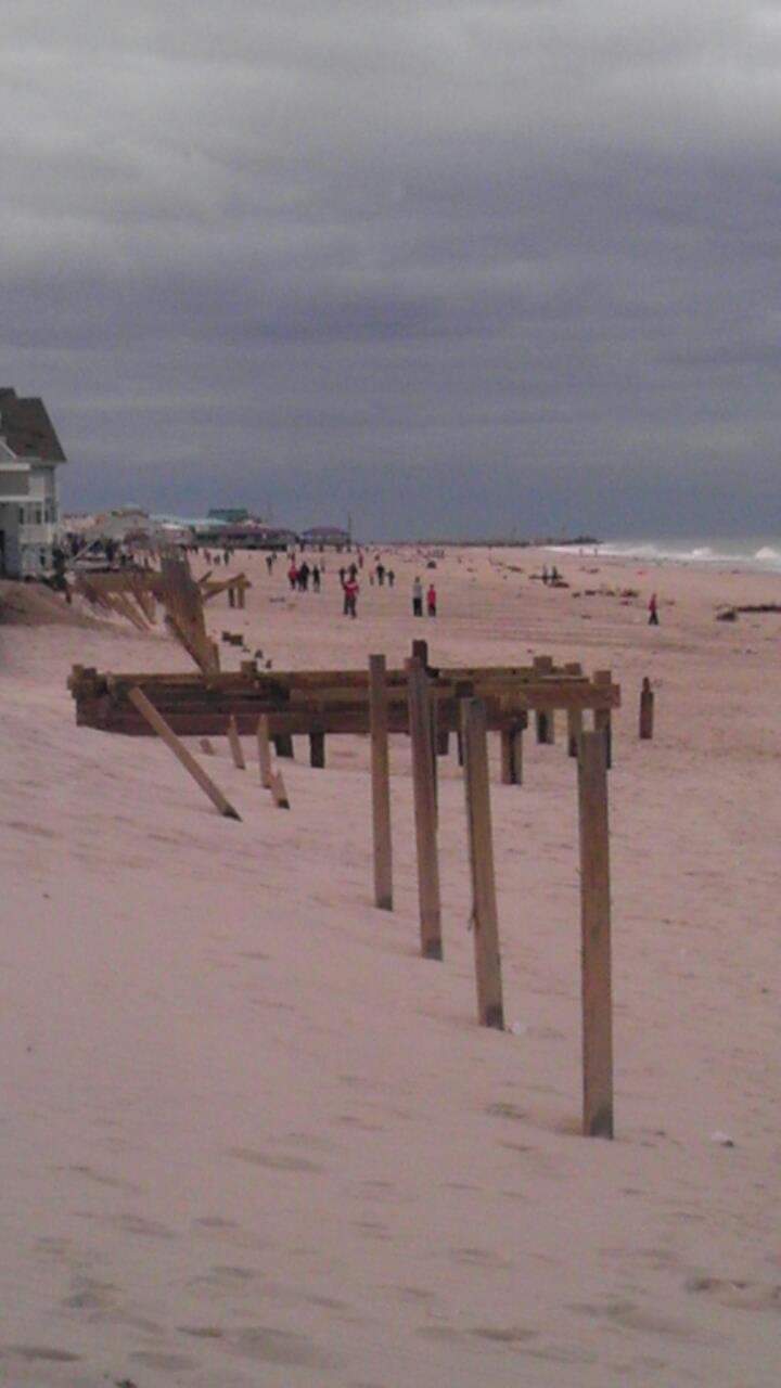Overcast beach with people and wooden structures.