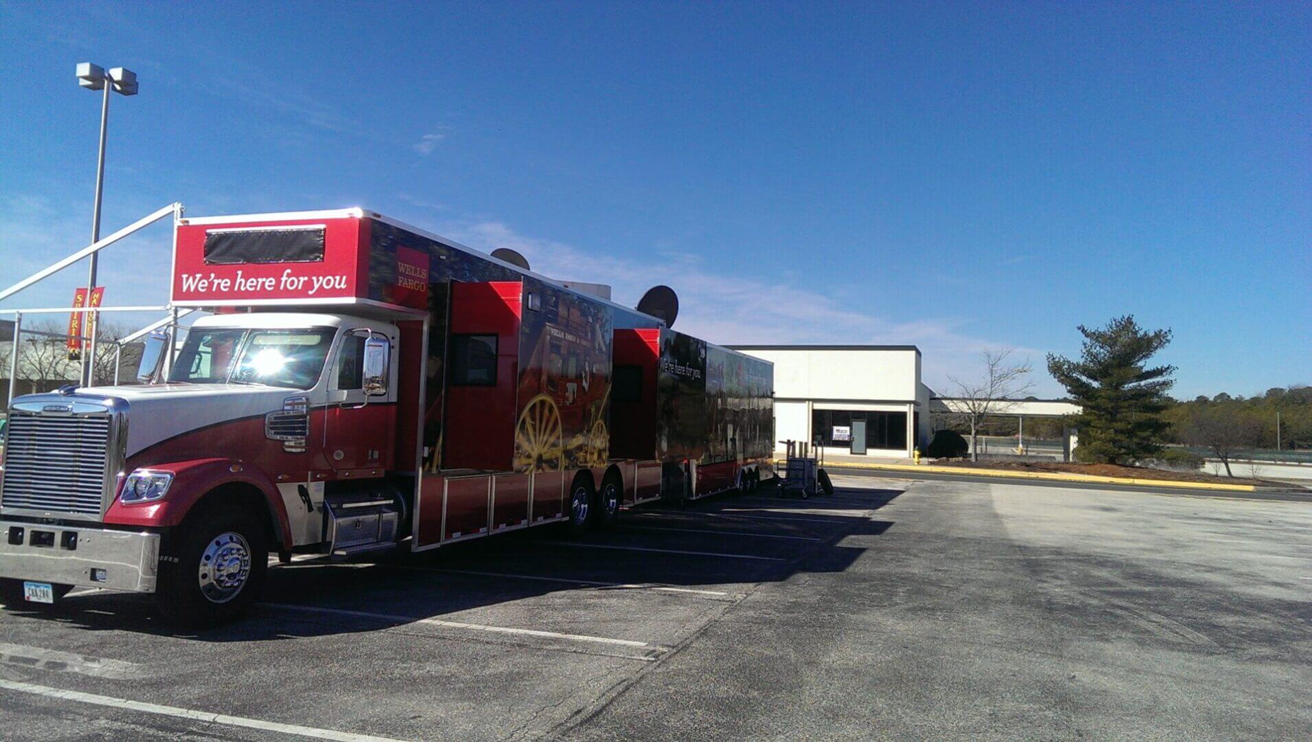 A large red food truck parked in an empty lot on a sunny day.