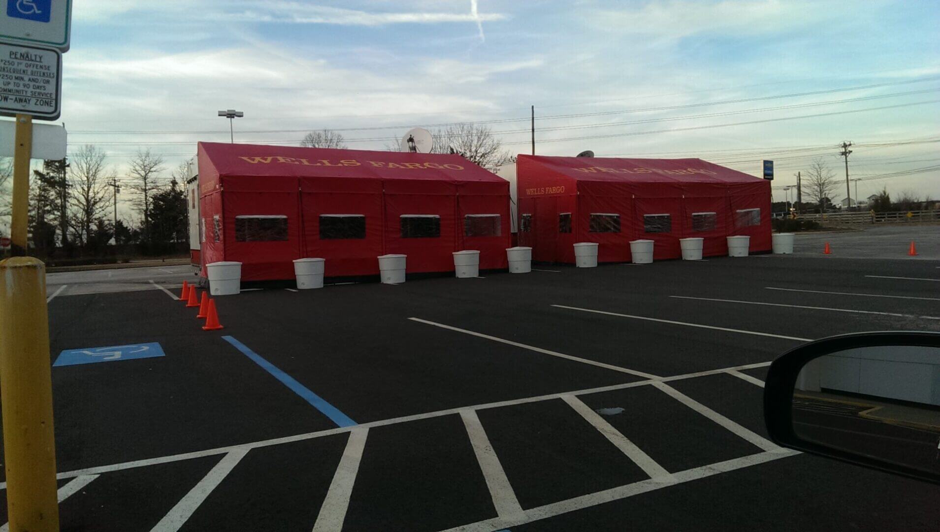 Two red outdoor tents set up in a parking lot under a cloudy sky.
